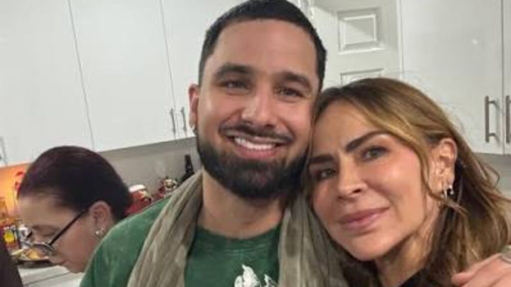 Smiling man and woman taking a selfie in a kitchen, close up portrait with cabinets in the background.